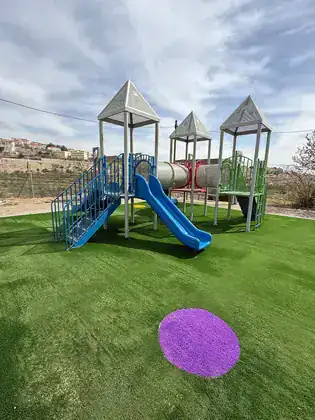 מתקן משחקים עם משטח בטיחות מדשא סינטטי